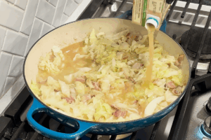 Pour in chicken broth for Crispy Braised Chicken with Bacon and Cabbage