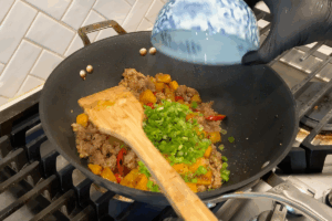 Add green onions for Golden Pumpkin Pork Stir-Fry