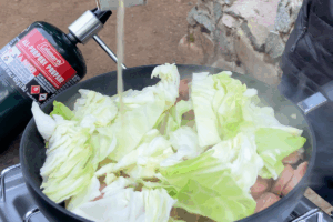 Pour in chicken broth for Buttery Sausage & Cabbage Stir-Fry